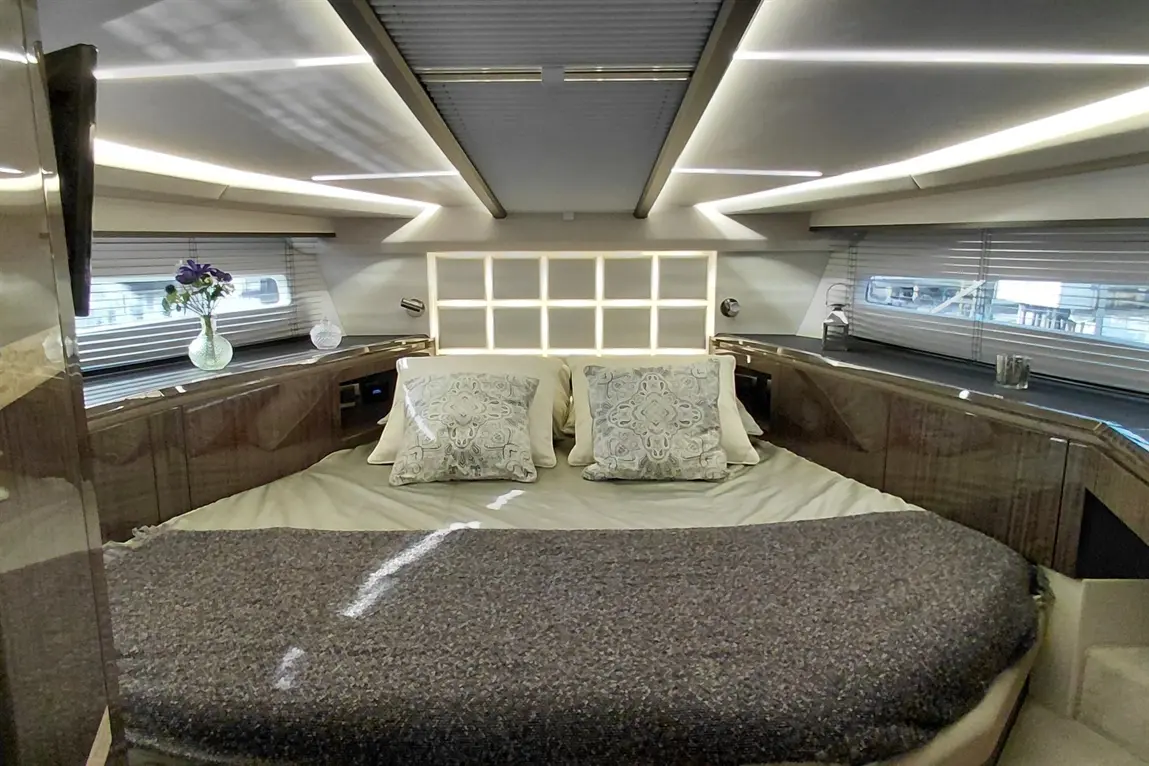 Luxurious yacht cabin featuring a double bed with decorative pillows, sleek cabinetry, and natural light from porthole windows.